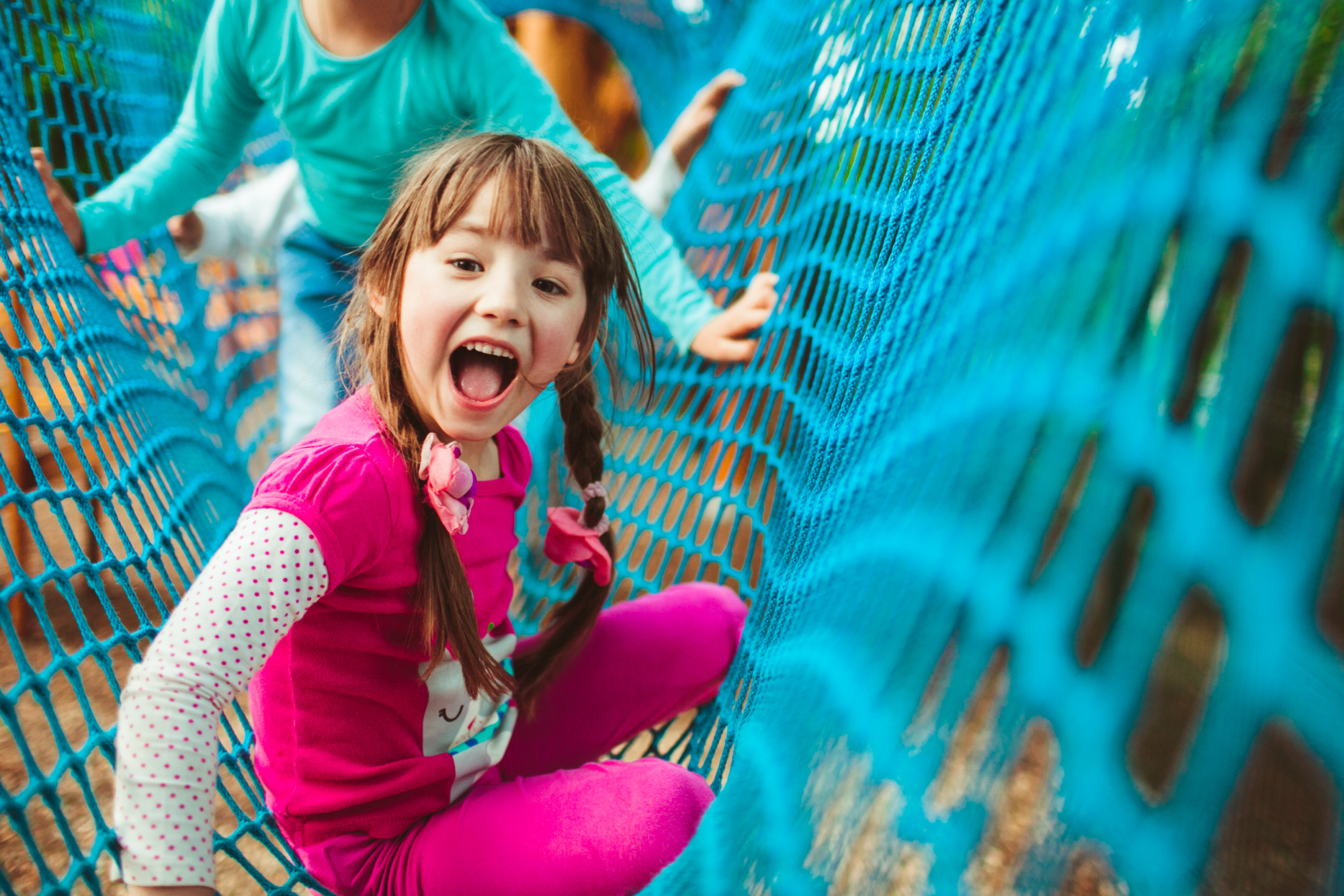Young girl on playground equipment showing confidence and joy in outdoor active play