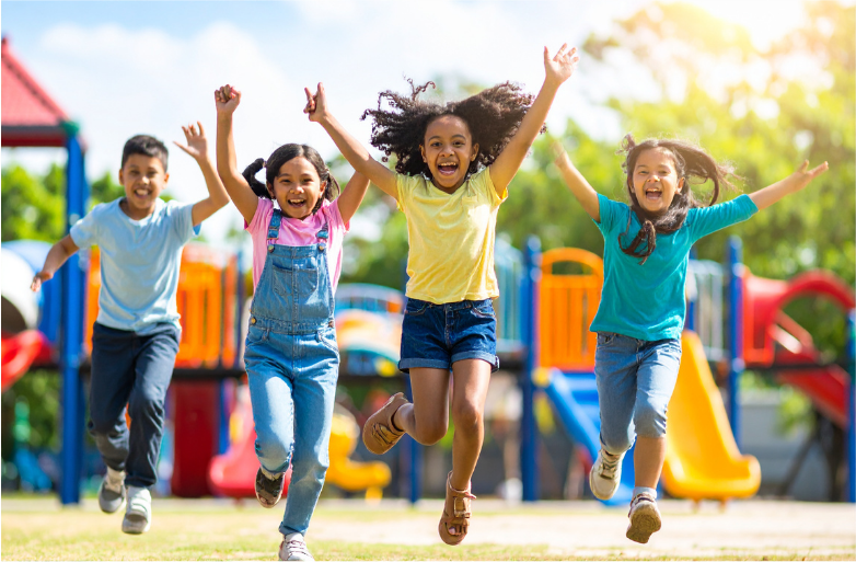 Children running outdoors with arms raised in excitement celebrating active play