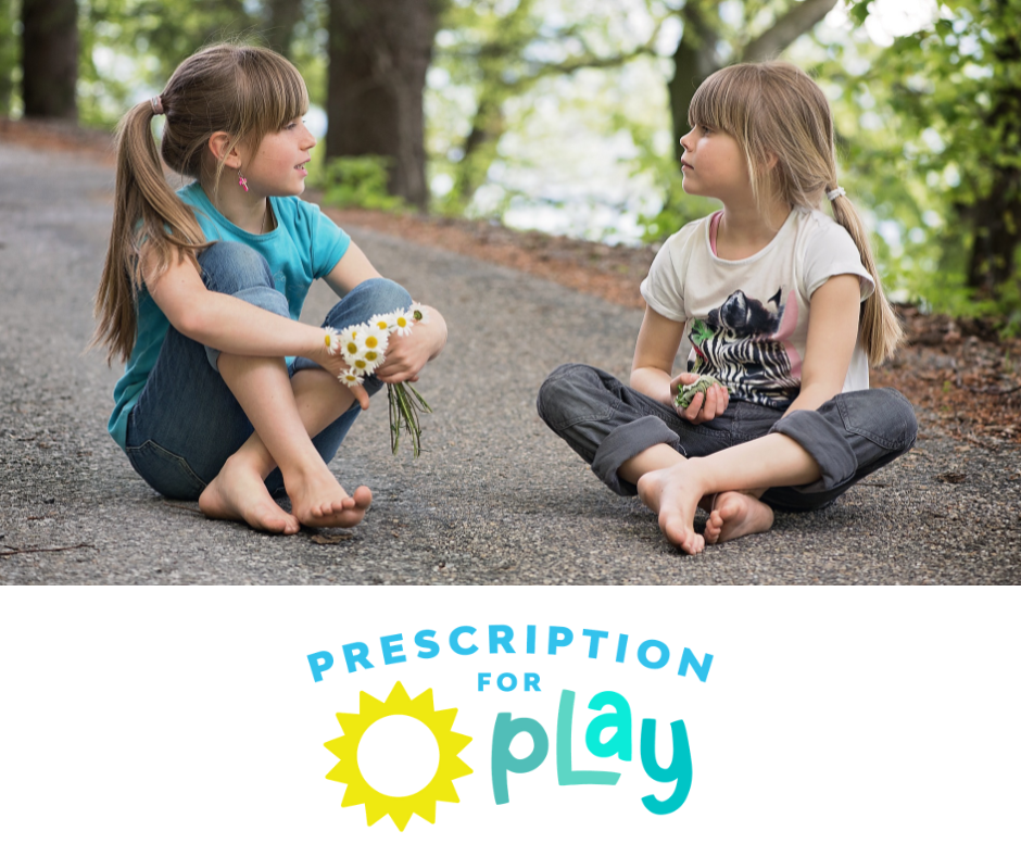 Two girls sitting on a forest path with daisies representing the joy of nature-based play